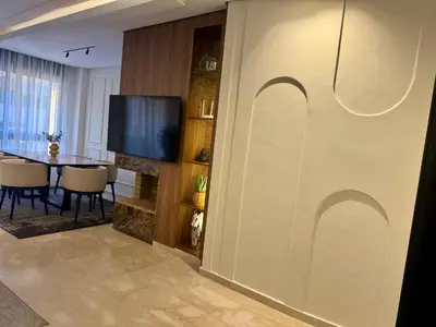a living room with a table and a television at CityZen Suites, Luxury 3BR near Mohamed V Stadium in Maarif