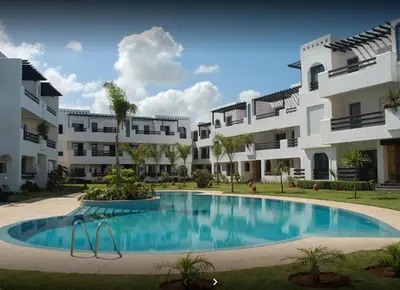 a swimming pool in front of a large apartment building at Beach apartment with pool Skhirat beach in Skhirat