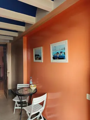 a table and chairs in a room with an orange wall at Beach apartment with pool Skhirat beach in Skhirat