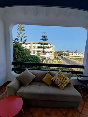 a couch in a living room with a large window at Beach apartment with pool Skhirat beach in Skhirat