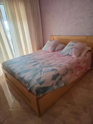 a bedroom with a bed with a wooden frame and a window at Residence kettani in Bouznika