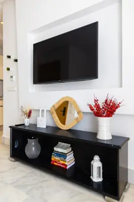 a black entertainment center with a television on a wall at APGCI -Studio Élégant a 5 min du Stade Mohamed V in Casablanca