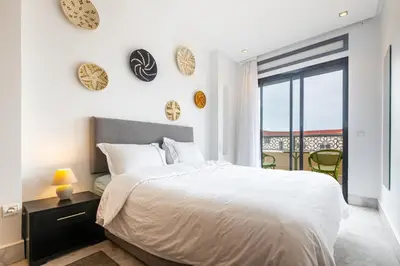 a bedroom with a white bed and a balcony at APGCI -Studio Élégant a 5 min du Stade Mohamed V in Casablanca