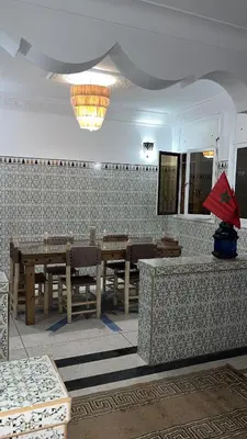 a dining room with tables and chairs and a chandelier at Villa Haryouli in Azemmour