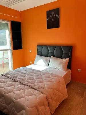 a bedroom with a large bed with an orange wall at Studio cosy et abordable in Casablanca