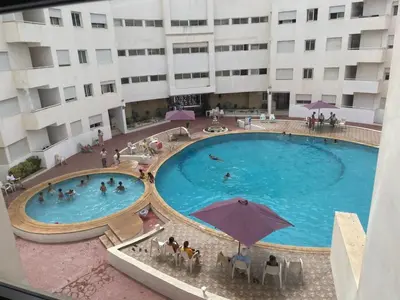 a large swimming pool in front of a building at Magnifique Appartement à Louer C14 Jnane Dalya in Bouznika
