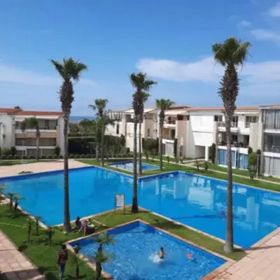 a large swimming pool with palm trees and buildings at Appartement à louer Aux perles de tamaris in Tamaris