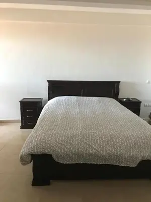 a bedroom with a bed and two night stands at Superbe Appartement à Louer C14 Jnane Dalya in Bouznika