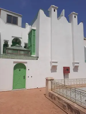 a white building with a green door on it at Casitademama in Sidi Yahia az Zaʼer