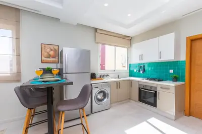 a kitchen with a refrigerator and a table with chairs at Seafront 2BR AC Sunny Corniche in Casablanca