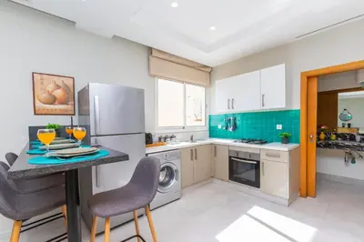a kitchen with a refrigerator and a table with chairs at Seafront 2BR AC Sunny Corniche in Casablanca