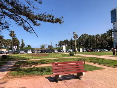 a park bench in a park with a parking lot at 2ch au Centre de Mohammedia Parc in Mohammedia