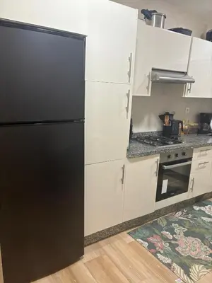 a black refrigerator in a kitchen with white cabinets at Nice apartment with terrace overlooking pool in O Ben Slimane
