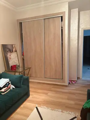 a living room with a green couch and a sliding door at Nice apartment with terrace overlooking pool in O Ben Slimane