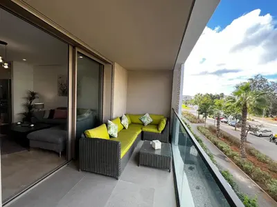 a living room with a yellow couch on a balcony at Modern 1BR Orangeraie - Terrace & Pool in Rabat