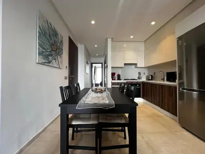 a kitchen with a black table with chairs and a refrigerator at Modern 1BR Orangeraie - Terrace & Pool in Rabat