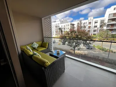 a balcony with a couch and a large window at Modern 1BR Orangeraie - Terrace & Pool in Rabat