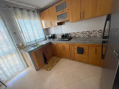 a small kitchen with wooden cabinets and a sink at Modern apartment in Rabat, Temara in Temara