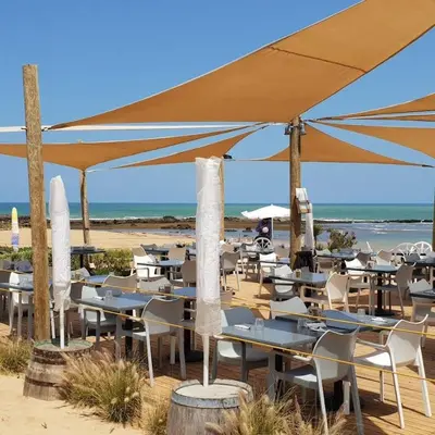 a group of tables and chairs with umbrellas on the beach at Pearl Of Eden Island in Bouznika