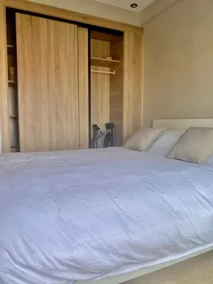 a bedroom with a large white bed with wooden cabinets at Bright & Cozy Apartment in Casablanca
