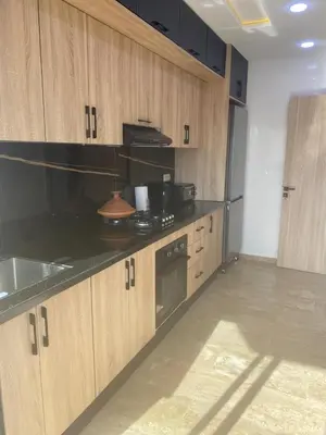 a kitchen with black counter tops and wooden cabinets at Bright & Cozy Apartment in Casablanca
