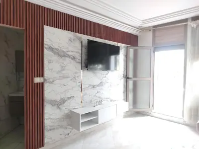 a bathroom with a tv and a marble wall at Très joli appartement à Casablanca in Casablanca