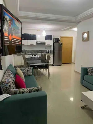 a living room with a green couch and a kitchen at Lovely three sides Appart in Ola Blanca in Sidi Rahal