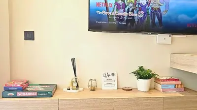 a tv on top of a wooden shelf with books at Appartement Cosy neuf - Salle de sport in Casablanca