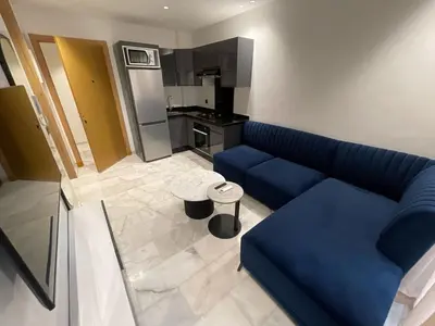 a living room with a blue couch and a kitchen at Luxury studio Maarif à 5 min CFC in Casablanca