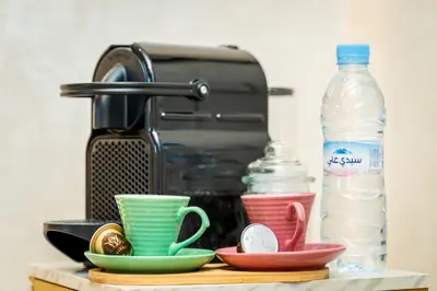 a kitchen counter with cups and a bottle of water at Modern Comfortable Apartment - Corniche Hassan II in Casablanca