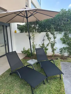 two chairs sitting under an umbrella in the grass at Luxurious Apartment with Serene Garden & Private Pool in Casablanca