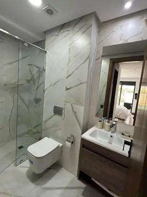 a bathroom with a toilet and a sink and a shower at Luxurious Apartment with Serene Garden & Private Pool in Casablanca