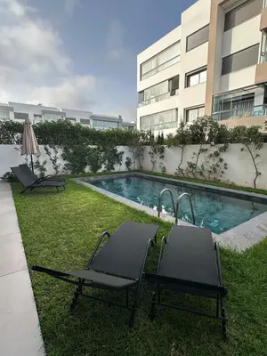 a swimming pool with two lounge chairs next to a building at Luxurious Apartment with Serene Garden & Private Pool in Casablanca