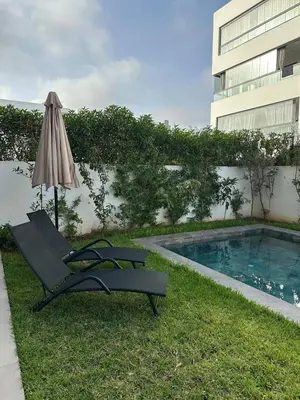 a chair and an umbrella next to a swimming pool at Luxurious Apartment with Serene Garden & Private Pool in Casablanca