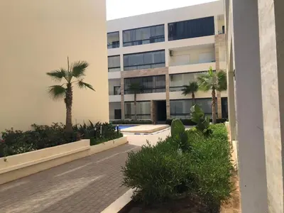 a building with palm trees in front of it at Cozy Studio with pool, fiber optics in Mansouria