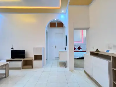 a white room with a bed and a desk and a door at Cosy apartment steps from shore & public transport in Rabat