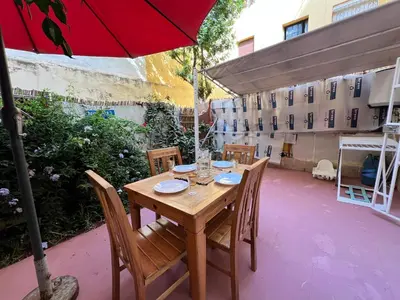 a wooden table with chairs and a red umbrella at Cosy apartment steps from shore & public transport in Rabat
