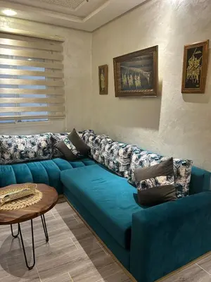 a blue couch in a living room with a table at Apartamento Temara Morroco in Temara