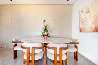 a table with chairs and a vase of flowers on it at Prestigieux appartement 3 chambre plein cœur CFC in Casablanca