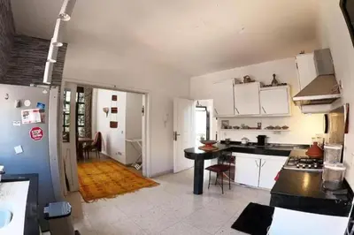 a kitchen with white cabinets and a black table at Cosy and Spacious 4BR villa 5 min to Hay Riad in Temara