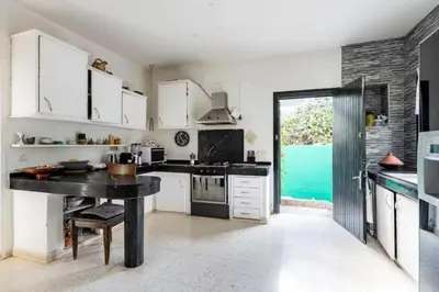 a kitchen with white cabinets and a black counter top at Cosy and Spacious 4BR villa 5 min to Hay Riad in Temara