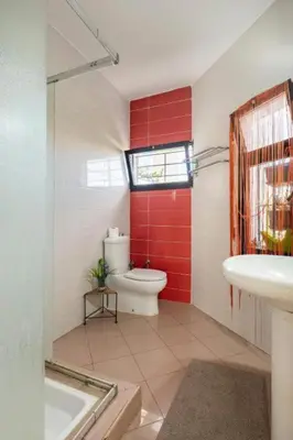 a bathroom with a white toilet and a red wall at Cosy and Spacious 4BR villa 5 min to Hay Riad in Temara