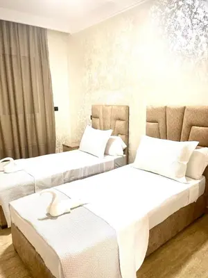 two beds in a hotel room with white furniture at Modern Central Apartment in Casablanca in Casablanca