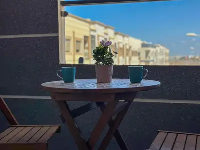 a table with two cups and a potted plant on it at Appartement chic Dahomey plage - Rabat & Bouznika, mer et culture in Bouznika