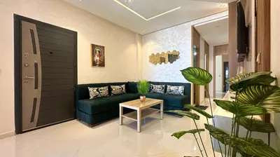 a living room with a green couch and a table at Appartement chic Dahomey plage - Rabat & Bouznika, mer et culture in Bouznika
