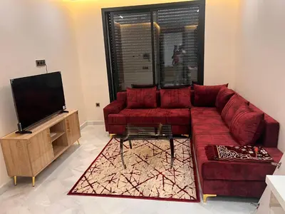 a living room with a red couch and a flat screen tv at Proche chekh khalifa KLIVING Studio in Casablanca