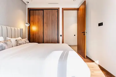 a bedroom with a white bed and a wooden door at Luxueux appartement 3 chambre en plein cœur CFC NEXT HOUSE 3 in Casablanca