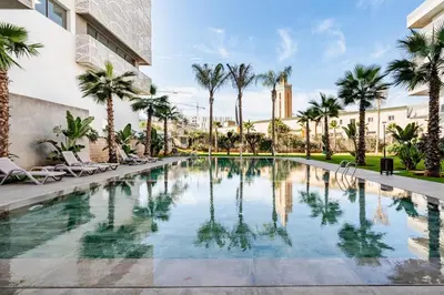 a swimming pool with palm trees and a building at Luxueux appartement 3 chambre en plein cœur CFC NEXT HOUSE 3 in Casablanca