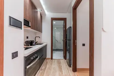 a kitchen with white walls and a wooden floor at Studio Signature - Parking privé & neuf in Casablanca