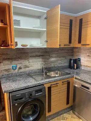 a kitchen with a sink and a washing machine at Appartement bord de mer avec piscine à Bouznika in Bouznika